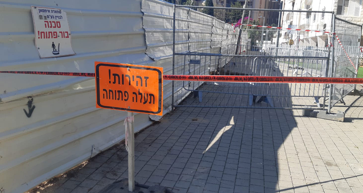 שלט זהירות! תעלה פתוח - סמוך לבור שנפער ליד אתר בניה ברחוב האודם