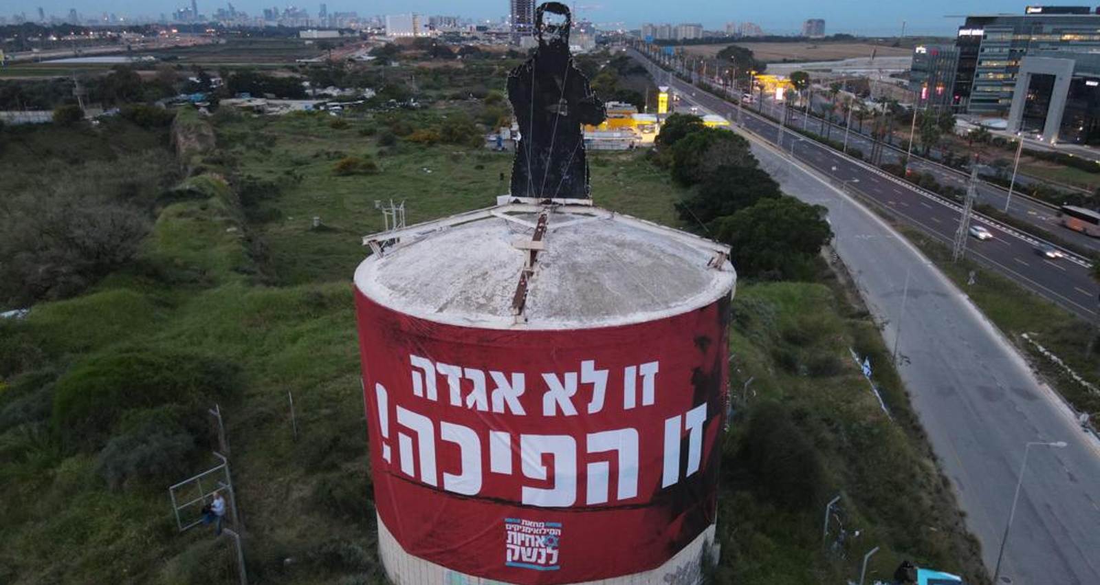 מתנגדי המהפכה המשפטית עם שלט ענק על מאגר המים בהרצליה