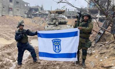דגל ישראל מונף על ידי חיילים הרצליינים בעזה. ברקע הטנק ועזה המרוסקת