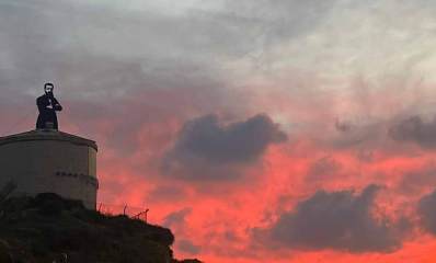 הרצל על מגדל המים בכניסה הדרומית מערבית להרצליה על רקע שקיעה ושמים אדומים ומעוננים