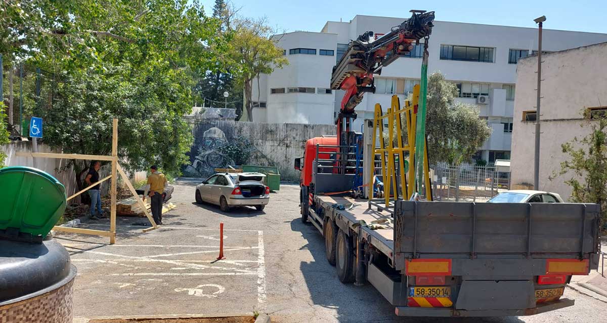 משאית מנוף פורקת ציוד לשיפוץ מוסדות חינוך