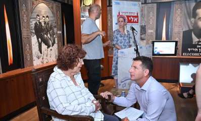 טקס זיכרון שנתי לאלי כהן, יריב פישר כורע ליד נדיה כהן אלמנתו של אלי כהן היושבת על כסא