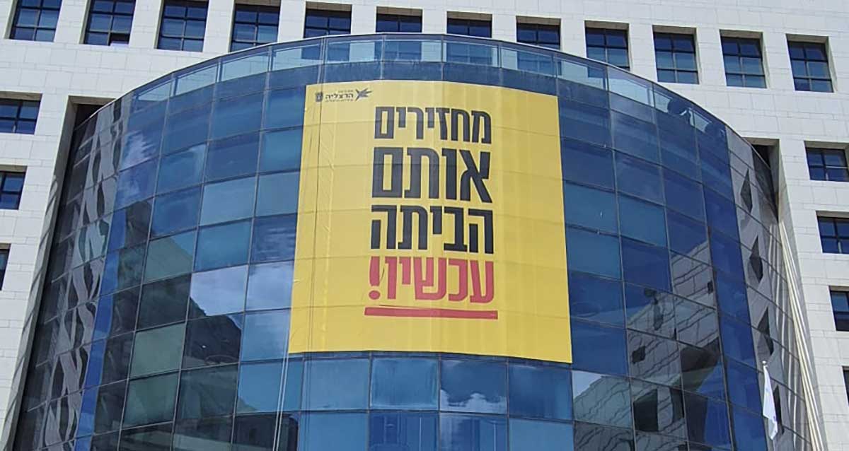 באנר ענק בחזית בניין עיריית הרצליה: מחזירים אותם הביתה עכשיו