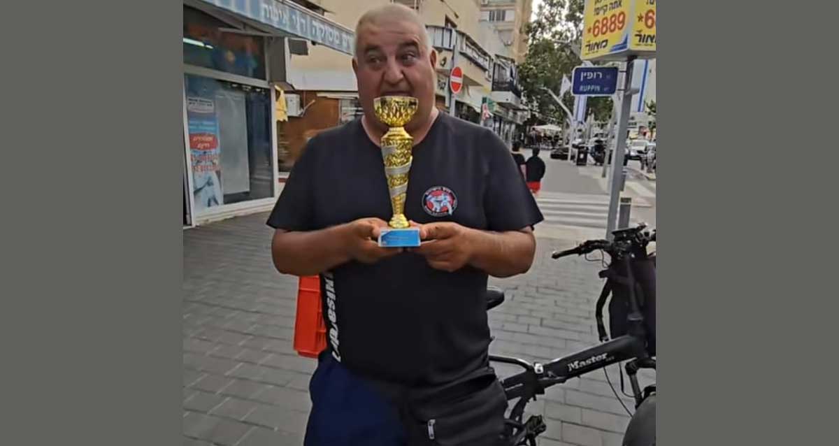אפי הנמר אוחז גביע ברחוב סוקולוב הרצליה, מאחוריו האופניים החשמליות שנגנבו