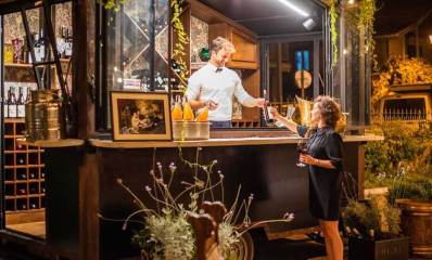 פופ אפ יינות. קרון הגשת יינות עם אשה שאוחזת בכוס יין וברמן פותח יין