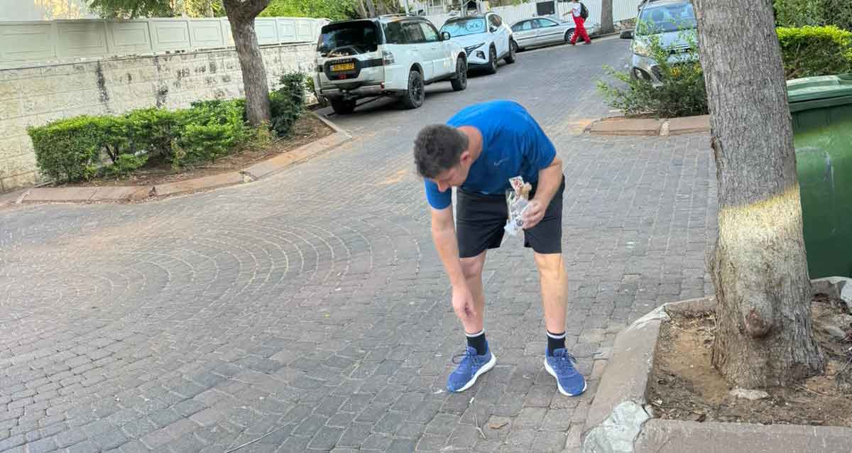 יריב פישר אוסף בדלי סיגריות שהשליכו המפגינים מול ביתו. צילום: עיריית הרצליה צילום: פרטי