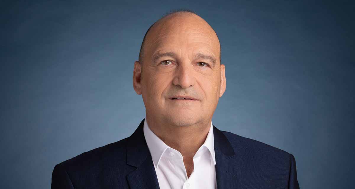 תמונה של עו"ד מיכה בלום היועץ המשפטי של עיריית רמת השרון, תמונה של חלק גוף עליון פנים וחזה. לבוש בחולצה לבנה עם כפתורים וז'קט שחור