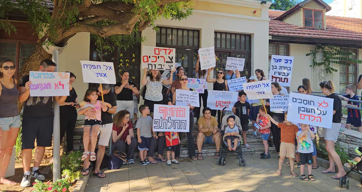 אמהות וילדים מחזיקים שלטים בהפגנת האמהות לילדי גני יול״א בכפר סבא. בשלטים כתוב: רפי סער בחרתי בך, עכשיו תורך, ממשיכים בעשייה לחורבן היול"א, אל תפקיר אותי, בגן שלי צהרון איכותי, צהרון איכותי בגן שלי. לולא רפי פיטר את כולן, היה נשאר צהרון מצויין, מחטף החלת"פ