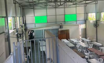 מבנה בית כנסת ובו שולחנות אורוכים וכיסאות פלסטיק בסככה המיועדת להריסה - מבט פנימה