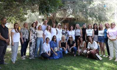 הצוות המקצועי הבכיר במינהל החינוך, צילום קבוצתי בגינה, ברקע עץ רחב ומאחוריו מבנה