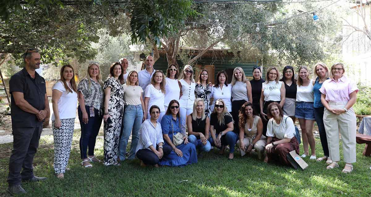 הצוות המקצועי הבכיר במינהל החינוך, צילום קבוצתי בגינה, ברקע עץ רחב ומאחוריו מבנה