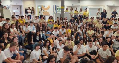 פתיחת שנת הלימודים בחטיבת אלון כפר סבא, צילום מלפנים של התלמידים היושבים על הרצפה המרוצפת של חצר בית הספר. רבים מהתלמידים לובשים חולצות צהובות. מאחורי התלמידים היושבים עומדים מורים ומורות גם חלק מהם בחולצות צהובות. ברקע קיר של בניין בית הספר.