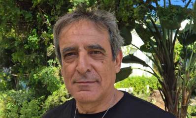 עמוס מגוז. תמונה של פלג גוף עליון, לובש טישרט שחור ועונד שרשרת