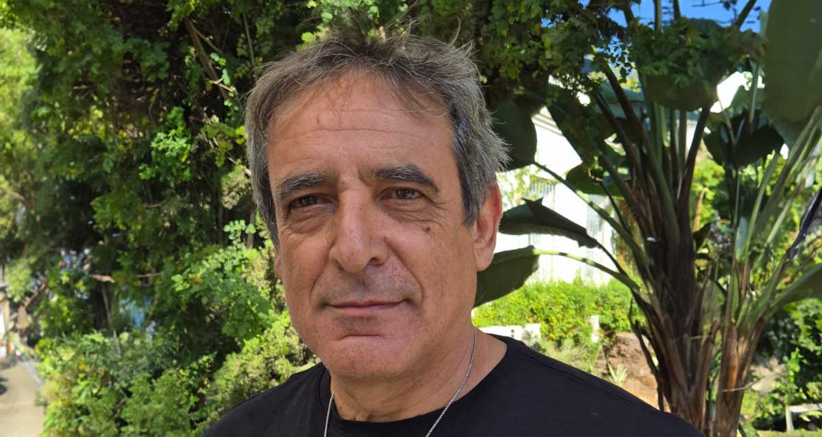 עמוס מגוז. תמונה של פלג גוף עליון, לובש טישרט שחור ועונד שרשרת