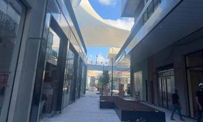 אתר קניון ביג גלילות. תמונה של רחבה בין שני בניינים בשלבי בנייה. באמצע הרחבה משטח שחור לישיבה וצורתה האות Z. מספר פועלים ברחבה.