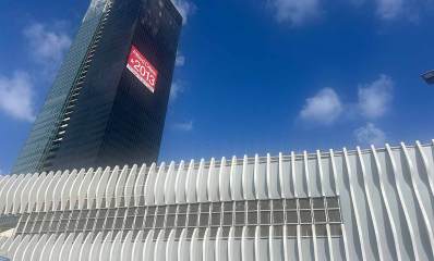 ביג גלילות רמת השרון, מגדל שחור גבוה של משרדים ושלט אדום של Allied Cities מספר טלפון 2013* וכיתוב: משרדים להשכרה. לפני המגדל בניין לכל רוחב התמונה מצופה בלוחות אנכיים ובאמצע ביניהם שורת חלונות זכוכית