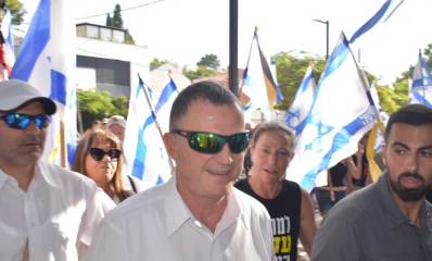 יולי אדלשטיין מלווה במאבטחים צועד בשבת מלווה על ידי מפגינים עם דגלי ישראל. צעדת הבושה