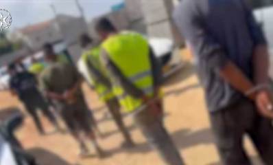 שוהים בלתי חוקיים אזוקים מאחורי הידים ומובלים לניידות המשטרה בהרצליה