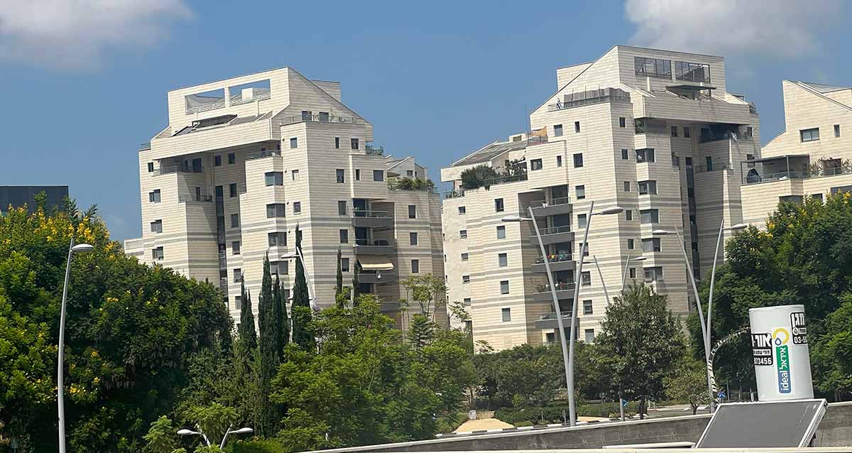 שכונת כפר סבא הירוקה, בניינים בני 10 קומות מצופים בלוחות בהירים, ולפניהם גינה עם עצים רבים.