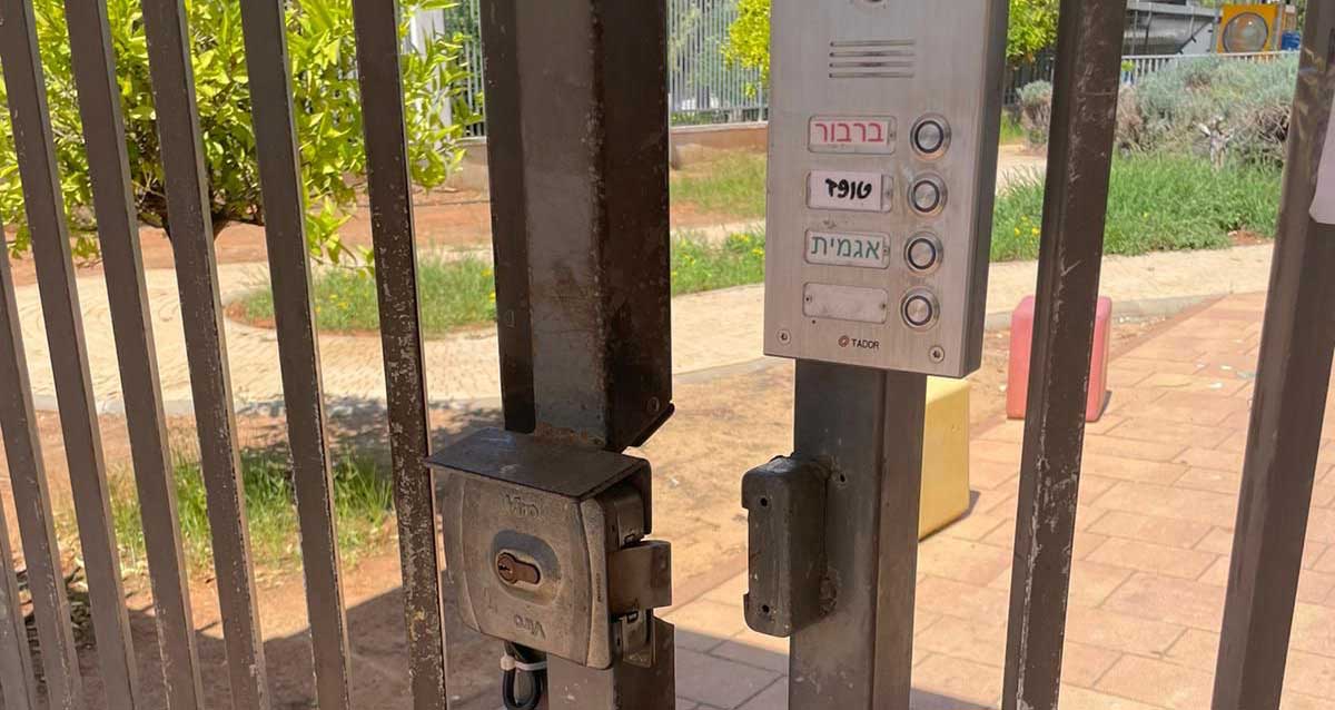 שער כניסה פתוח והאינטרקום ועליו שמות הגנים באשכול: ברבור, טופז ואגמית