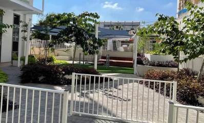 רוטשילד 55 כפר סבא. בין שני בתי מגורים גבוהים, גינת משחקים. גדרות מתכת משלושה חלקים סוגרים את שביל הכניסה לגינה. שיחים ועצים בשני הצדדים של שביל הגישה לגינה. מעל הגינה יריעות בד כחולות העושות צל והן תלויות על עמודי מתכת בצדדים. בגינה דשא ומתקן עם מוט אופקי על שרשרות. ברקע חלק עליון של בניין מגורים.