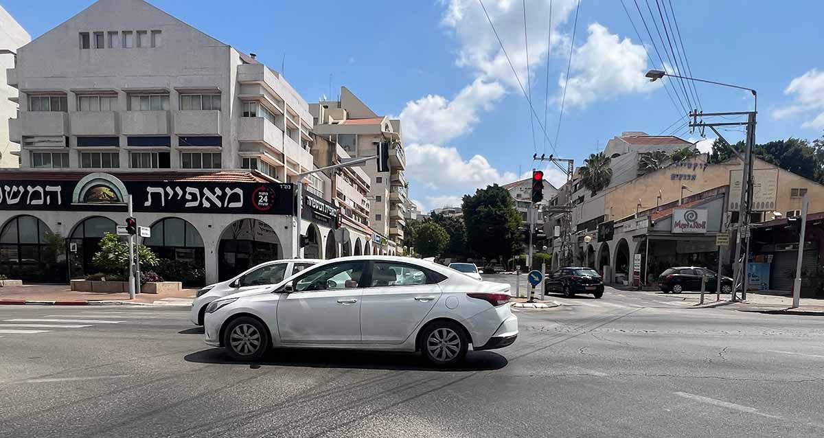 רחוב ששת הימים כפר סבא, משמאל בניין פינתי של 4 קומות ובקומת הקרקע מאפיית המשפחה. קומת הקרקע עם קשתות בשני הצדדים. הצילום הוא בצומת רחובות. בצד ימין בניין בן שתי קומות ובקומת הקרקע חנויות וקשתות בצד הבניין.