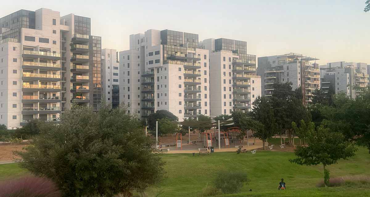 שכונת גליל ים בהרצליה. ברקע שורה של בנייני מגורים גבוהים של 10, 12 קומות. לפניהם פארק עם דשא, עצים ומתקני ספורט.