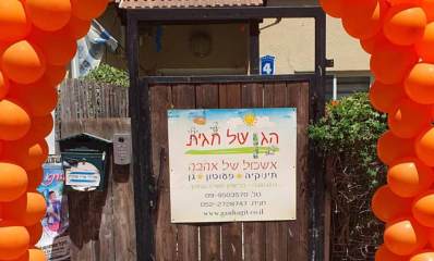 הגן של חגית ברחוב קלישר בהרצליה. הכניסה לגן בדלת מעץ ועליה שלט. משמאל לשלט קודן ותיבת דואר. מסביב לשער הכניסה בלונים כתומים מסודרים בצורת האות ח'. על שלט הכניסה הכיתוב: הגן של חגית, אשכול של אהבה, תינוקיה, פעוטון, גן, ברישיון משרד החינוך. ובחלק התחתון של השלט, מספרי הטלפון, וכתובת המייל.