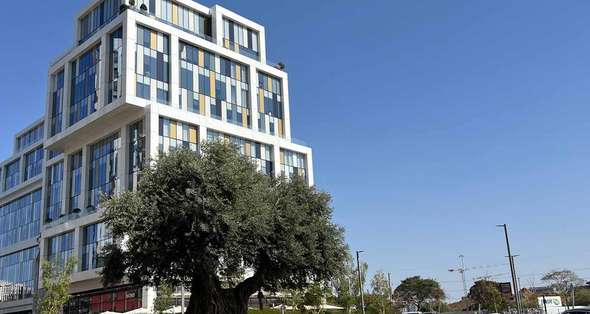 מתחם הרצליה הייטס. בניין ענק הנראה כמו קוביות על קוביות, וחלונות זכוכית בצבעים. לפניו עץ המסתיר חלק מהבניין.