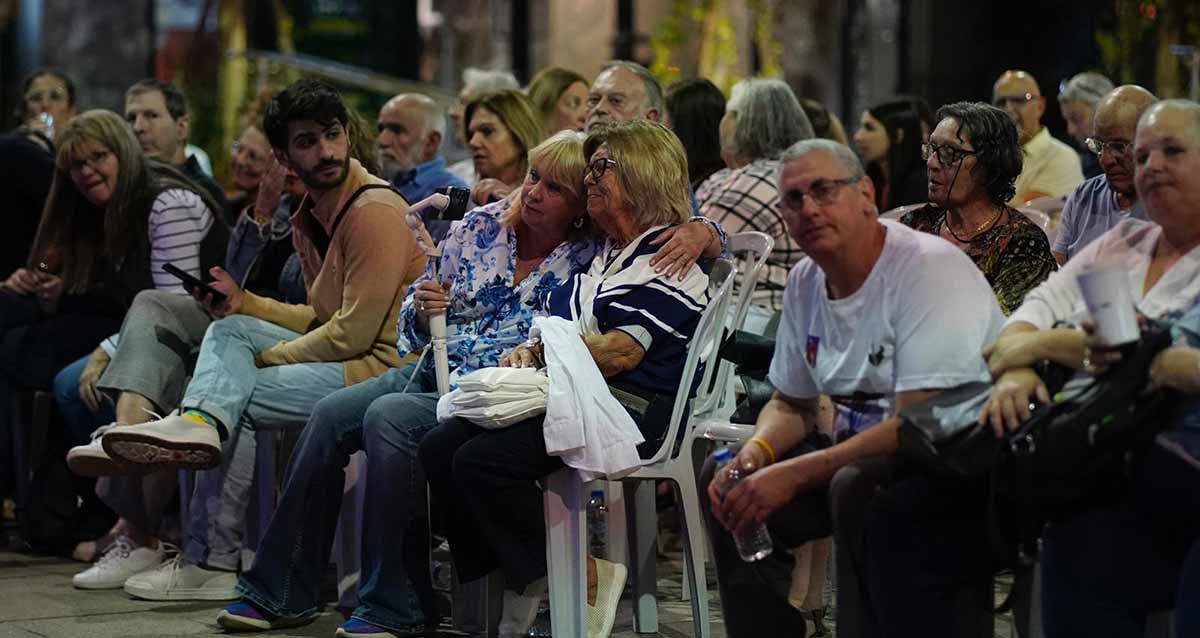 מציינים בהרצליה שנה למלחמה. קהל יושב על כסאות פלסטיק לבנים בטקס ברחבת העירייה.