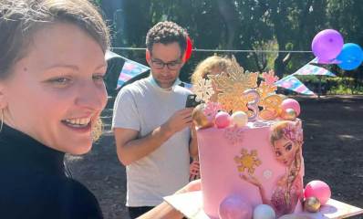 נדיה סוקלנקו מחזיקה עוגה ורודה וגדולה של יום הולדת 3 של ביתה