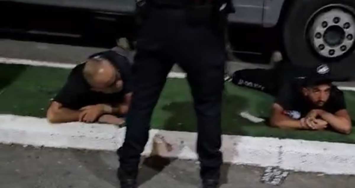 שני עצורים שוכבים אזוקים על המדרכה לרגלי שוטר במלון השרון, הרצליה