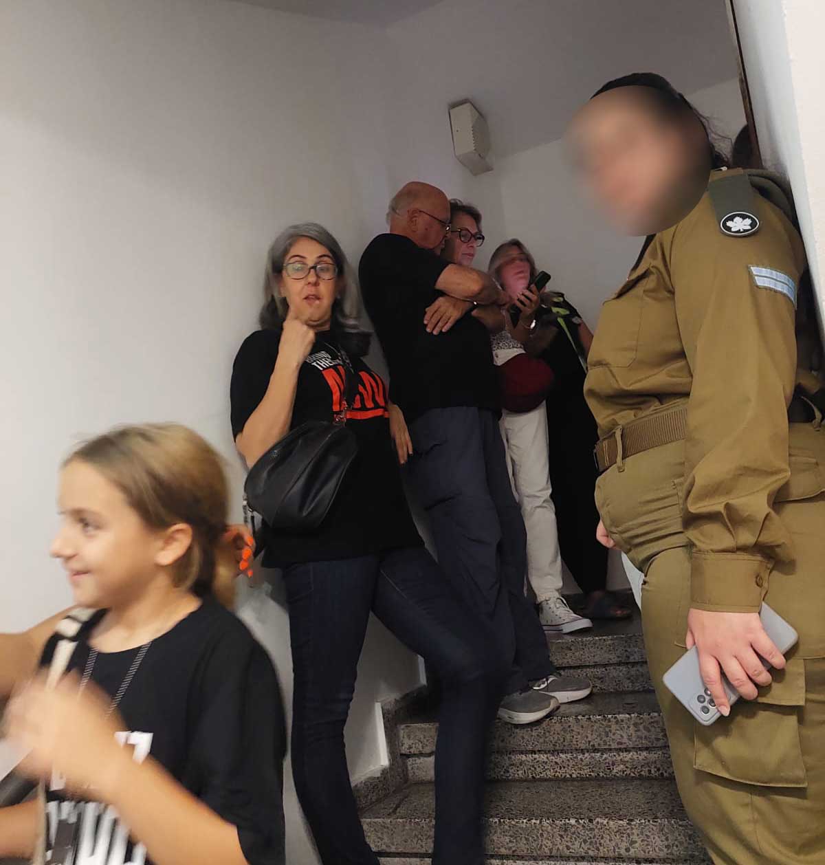 ילדים, חיילת ומבוגרים במתמגנים בחדר מדרגות בעת אזעקה בהרצליה