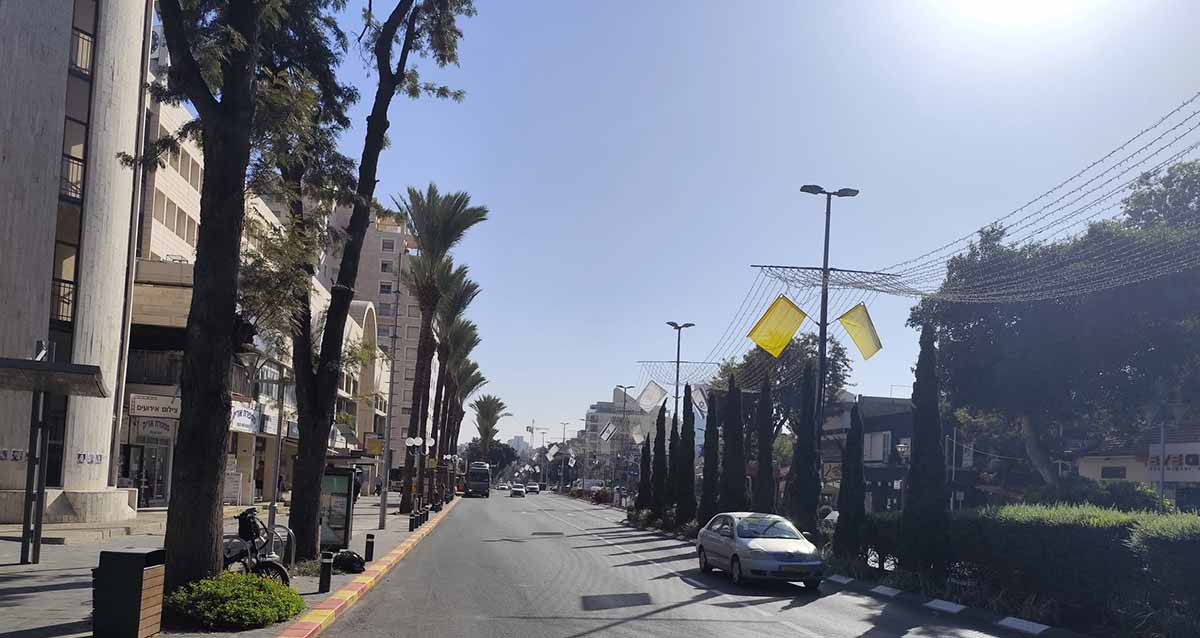 רחוב אחוזה ברעננה. בנייני מגורים משני צידי הכביש וחנויות בקומת הקרקע. דקלים לאורך המדרכה.