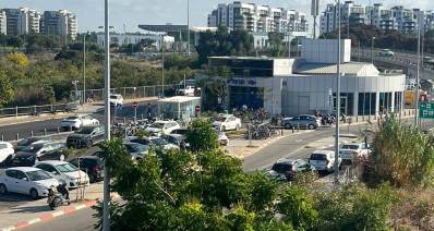 תחנת הרכבת בהרצליה. מבנה מעוגל בצידו האחורי עם חלונות זכוכית לכל הגובה. הכניסה בצד שמאל של המבנה בן קומה אחת. משמאל למבנה כבישי גישה לתחנה וחניון קטן לכלי רכב. ברקע בנייני מגורים גבוהים.