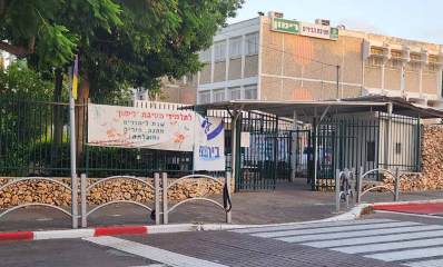 חטיבת הביניים רימון ברעננה. תמונה של בניין בית הספר שצולמה מהכביש שלפני בית הספר. מעבר חצייה להולכי רגל אל שערי בית הספר. חומה מבטון ואבנים מסביב לבית הספר וגדר מתכת על החומה. שערי מתכת של בית הספר. הבניין בן שלוש קומות, על הקומה העליונה שלט גדול, מימין סמל, באמצע על רקע לבן הכיתוב: חטיבת הביניים, ומשמאל על רקע ירוק באותיות גדולות הכיתוב: רימון. על גדר בחזית תלוי שלט מבד לבן ועליו הכיתוב: לתלמידי חטיבת "רימון" שנת לימודים מהנה, פוריה ומוצלחת.