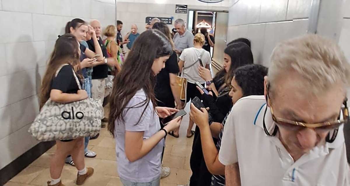 מבוגרים ובני נוער מצטופפים בכניסה למרחב המוגן בקניון שבעת הכוכבים הרצליה בזמן אזעקה