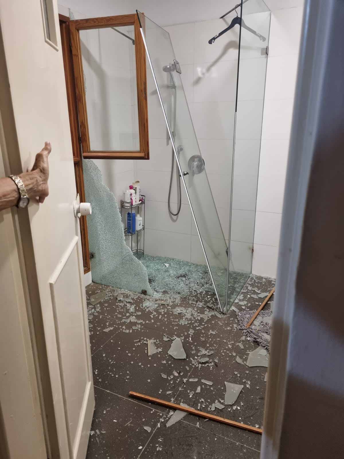 פגיעות הדף של טילים בליסטיים בחדר רחצה. מקלחון זכוכית שבור, זכוכית על הרצפה.