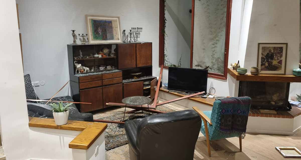 פגיעות הדף של טילים בליסטיים בסלון בית. מסגרת של חלון בתוך הסלון על הרהיטים.