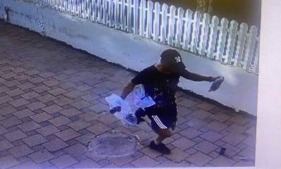 תושב טירה בלבוש שחור עם כובע חוטף שקית עם כסף מתושבת רעננה ובורח. השודד אוחז בידיו שקית פלסטיק וחבילה קטנה, ורץ על מדרכה מרוצפת. במקביל למדרכה חומה מבטון בצבע לבן וגדר עץ לבנה על החומה.