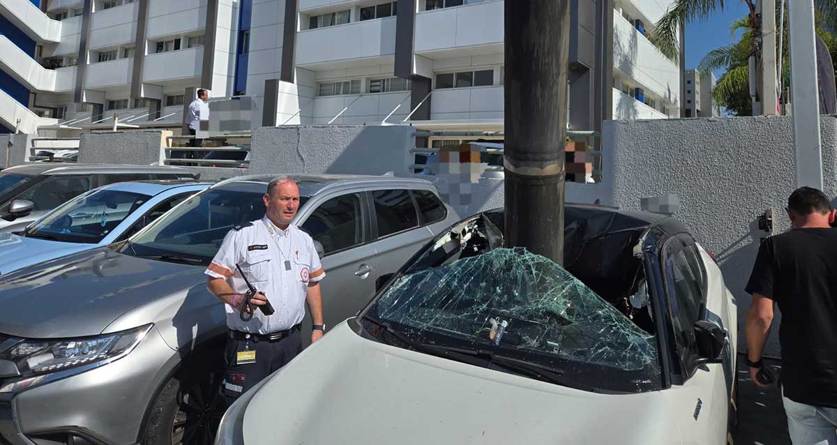 רסיסי יירוט תקועים בגג מכונית חונה במגרש חנייה ברעננה. ליד המכונית איש צוות מד"א