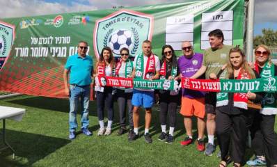 טורניר כדורגל לזכרם של איתם מגיני ותומר מורד. צילום של המשפחות על מגרש כדורגל, הם אוחזים סרט אדום ירוק עם הכיתוב: לעולם לא תצעדו לבד, איתם מגיני תומר מורד. מאחוריהם יריעה ענקית גם היא בצבעים ירוק ואדום, ועליה שני סמלים שבמרכזם כדורגל ושני ענפים מימינו ושמאלו, ומעל הכדור הכיתוב באנגלית: TOMER & EYTAM. בין שני הסמלים הכיתוב: טורניר לזכרם של איתם מגיני ותומר מורד. בצד ימין של היריעה שתי טבלאות, אחת של בית 1 והשנייה של בית 2. כל טבלה עם שלוש שורות ריקות לרישום.