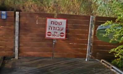 הכניסה לשביל ה"דק" חסומה על ידי גדר מלוחות עץ בצבע חום. על הנגדר שלט עם שני עיגולים המסמנים אין כניסה, וכיתוב: שטח עבודה אין כניסה.