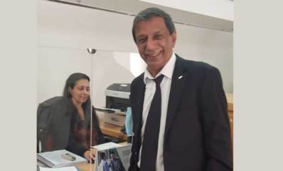 עו״ד ראובן חן מחייך ליד דלפק קבלה שמאחוריה יושבת אשה