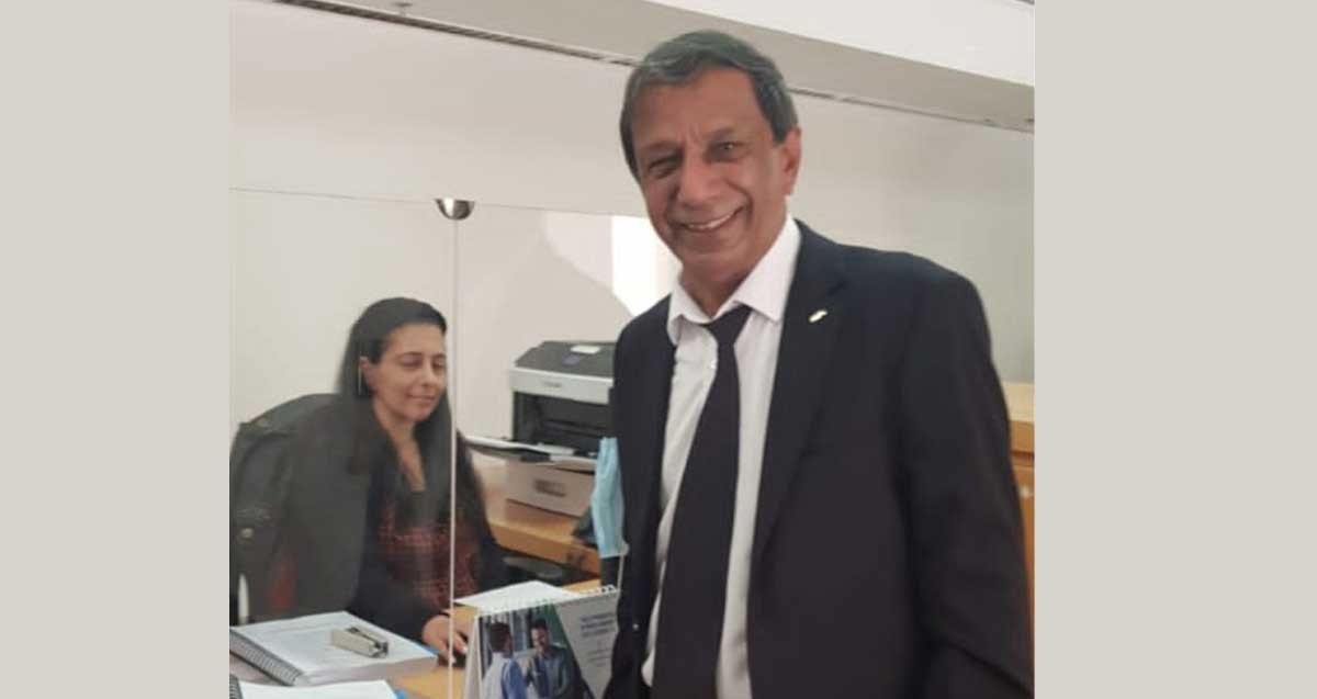 עו״ד ראובן חן מחייך ליד דלפק קבלה שמאחוריה יושבת אישה