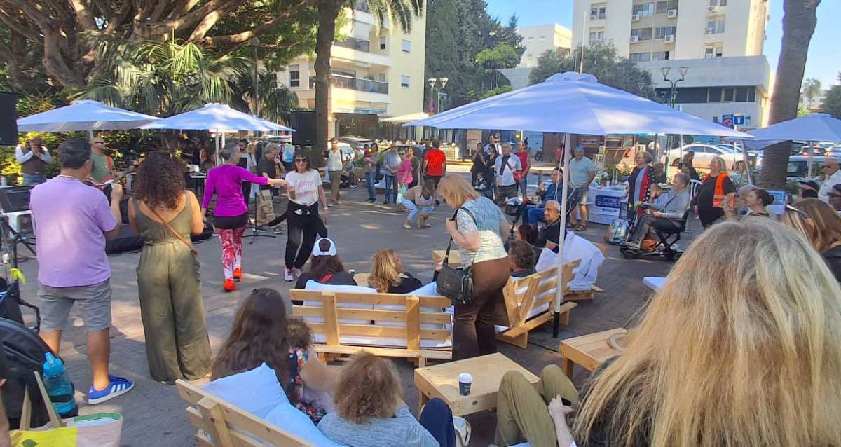 נשים רוקדות וקהל צופה בהופעת רחוב של רון רוזנפלד סולן להקת פורטרט בשדרות חן בהרצליה