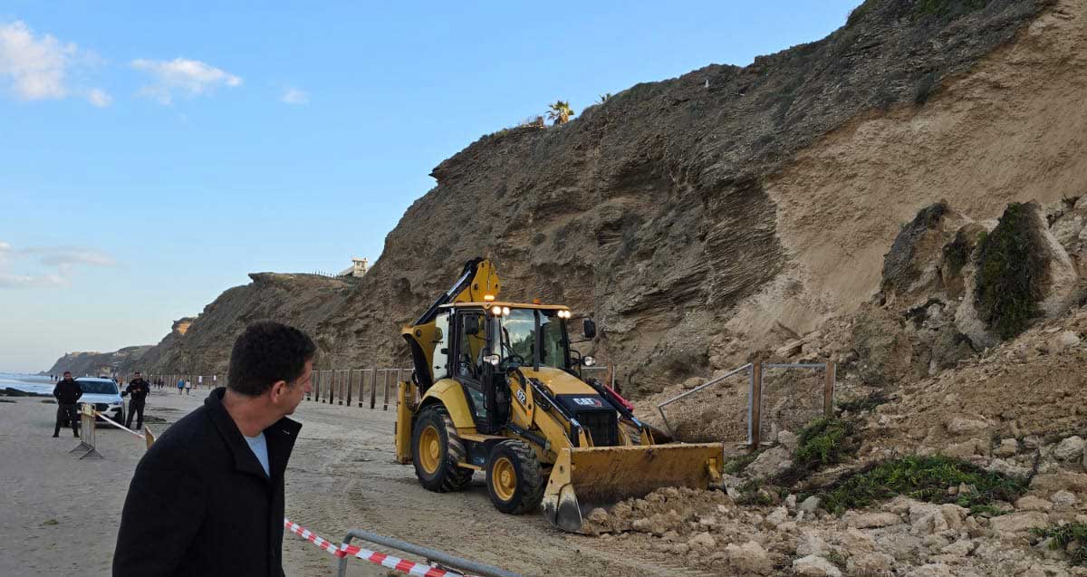 יריב פישר מתבונן בטרקטור שמפנה שברי כורכר מהמצוק שהתמוטט, ברקע אני הפיקוח העירוני