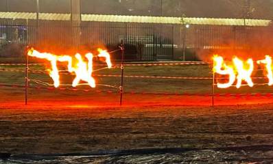 טקס קריאת שכבה ד' בשבט צופי הראל ברעננה על שם יאיר אביטן ז"ל. על גדר שתי כתובות דלוקות, האחת הראל והשנייה יאיר.