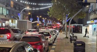 רחוב סוקולוב בהרצליה. עמוס מכוניות בשני נתיבים. רחוב חד סיטרי. מעל הרחוב תלויות מנורות בשרשרות.