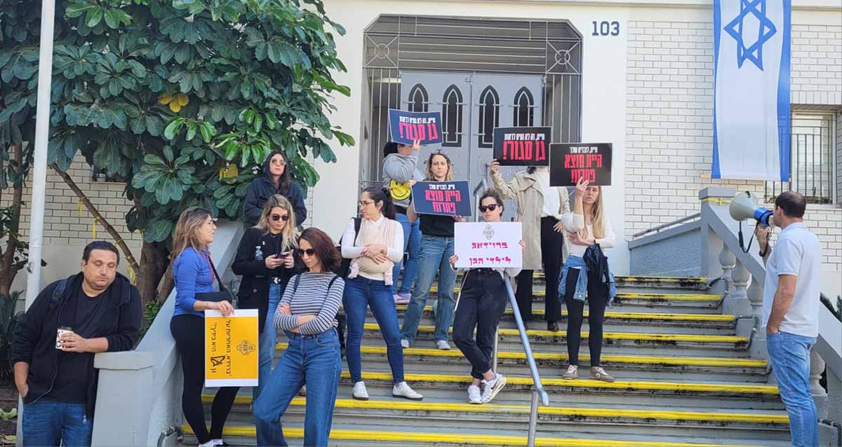 הפגנת אמהות לילדי גן נבל משכונת נווה זמר מחוץ לבניין עיריית רעננה. אמהות עם שלטים על מדרגות הכניסה לבניין העירייה. וגבר אחד עם מיקרופון נייד.